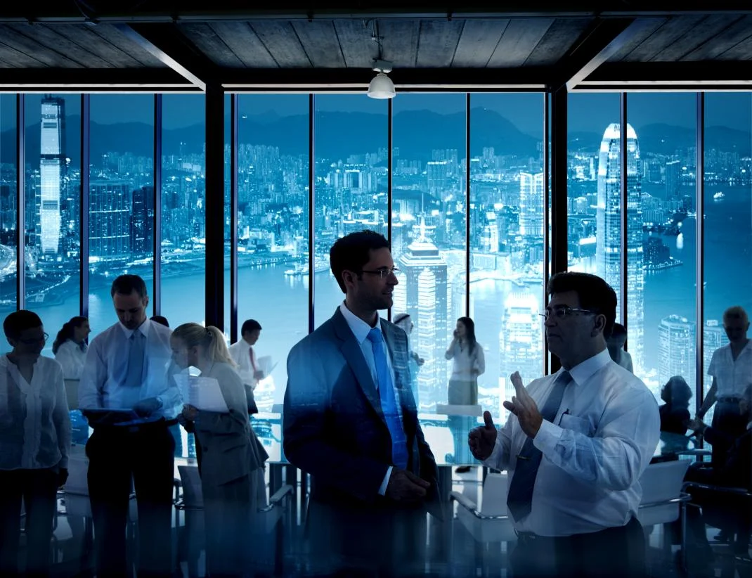 Professionals talking at an evening networking event overlooking the city